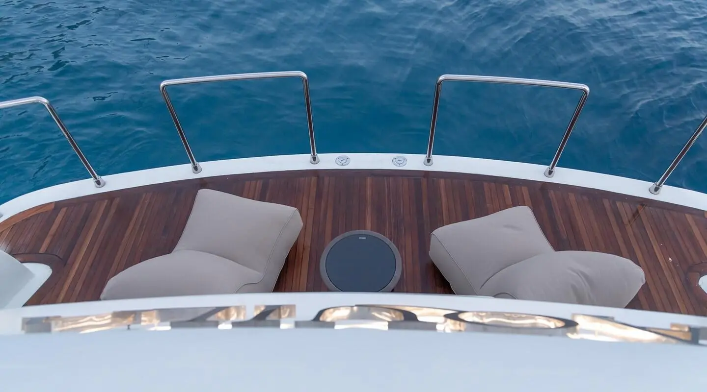 Aquila yacht aft deck with two cushioned seats on wooden planks and blue ocean backdrop