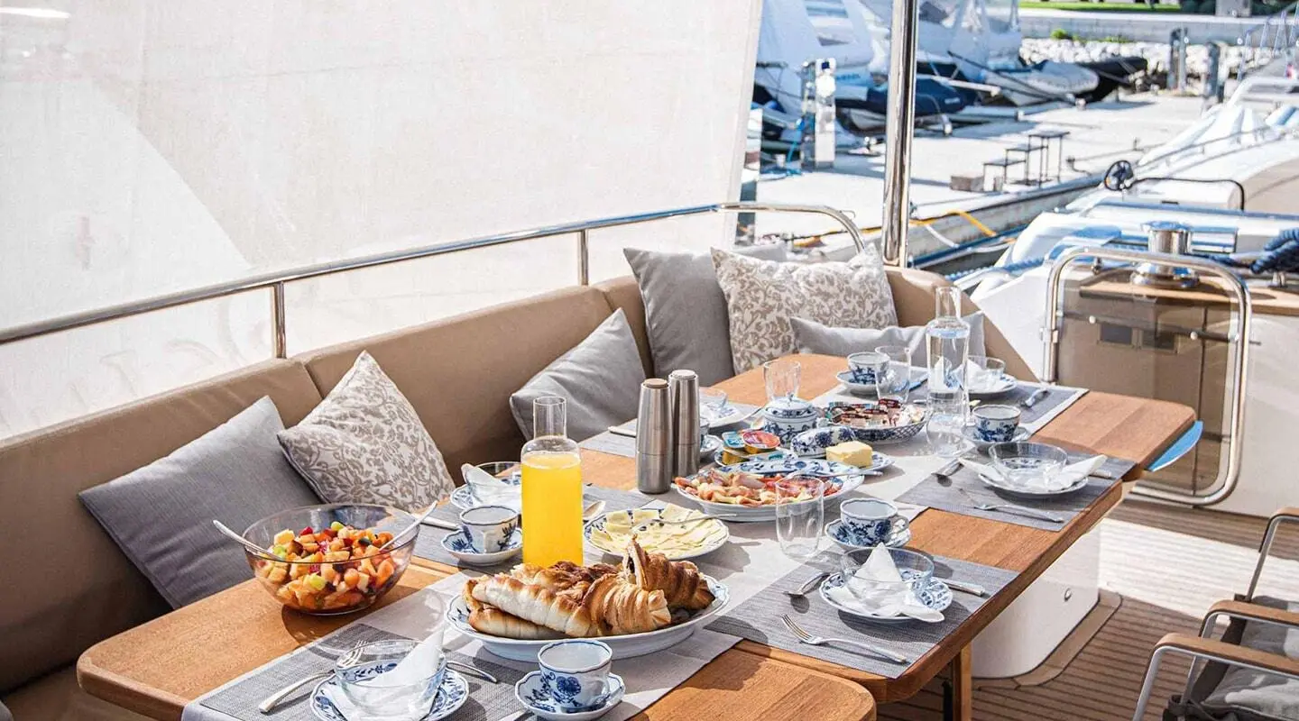 Dining area on aft deck of Insieme yacht with table setting and orange juice