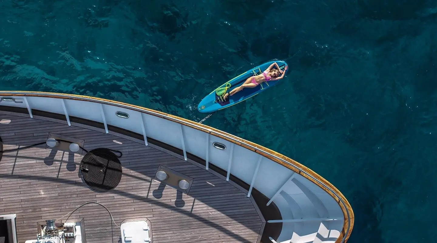 Yacht Karizma at sunset, white hull beside turquoise sea, moored along pier