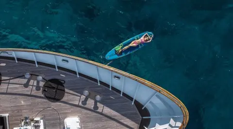 Yacht Karizma at sunset, white hull beside turquoise sea, moored along pier