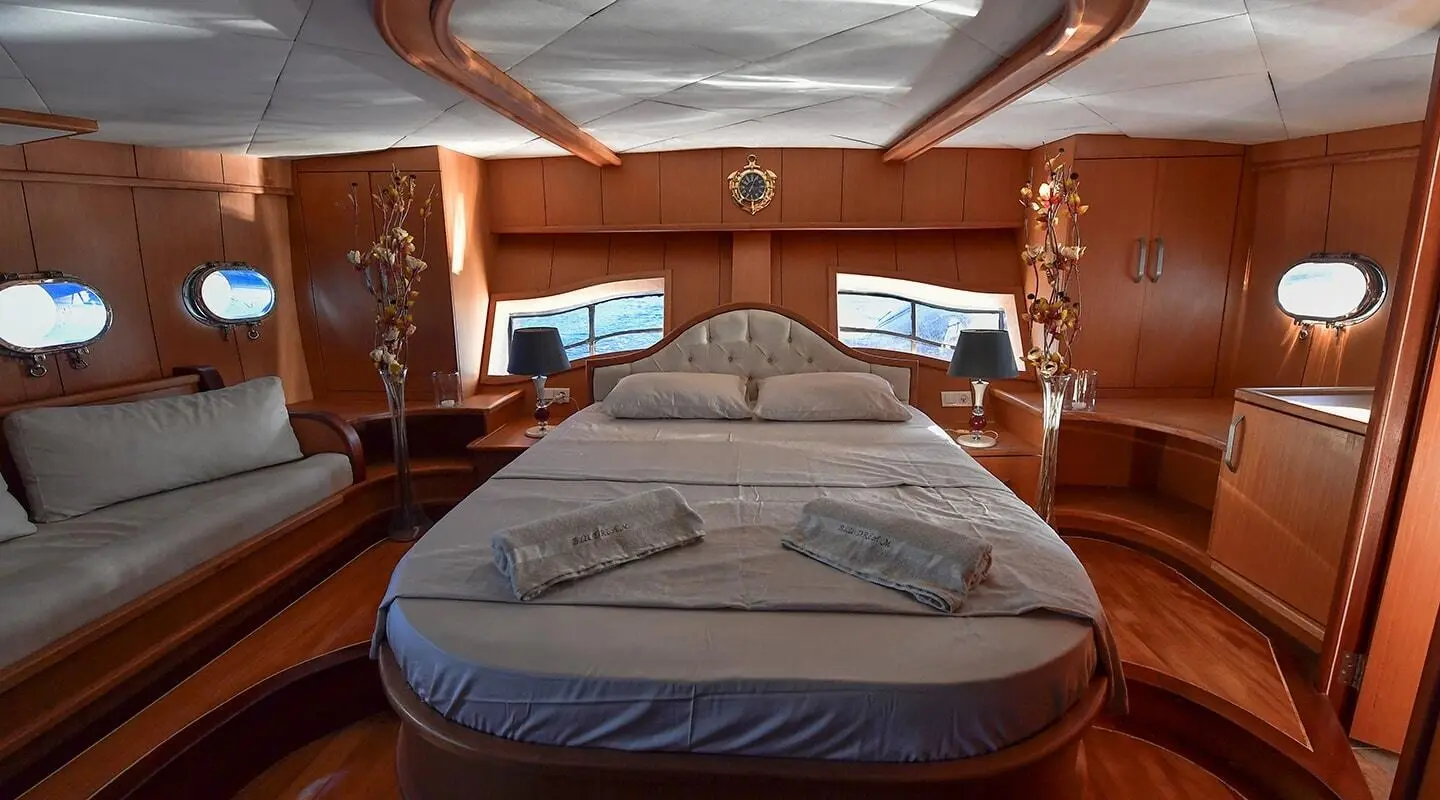 Blu Dream yacht interior bow with large bed, wood panels, and warm lighting
