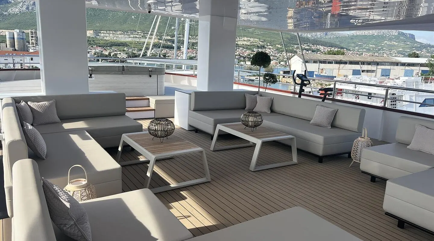Melody yacht aft lounge with cream sofas and wooden coffee tables on teak deck