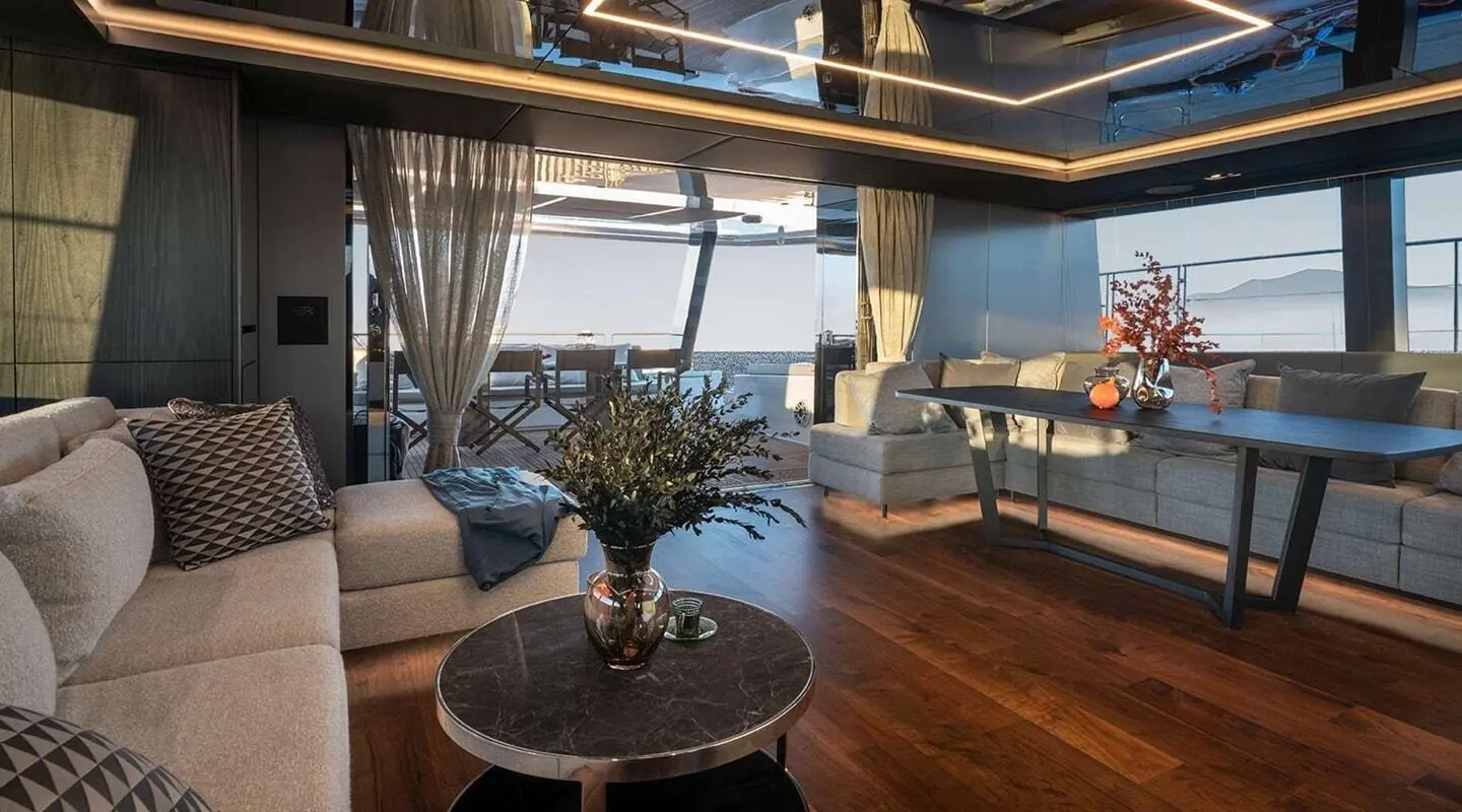 Elegant yacht saloon with seating, wooden floor, and large windows