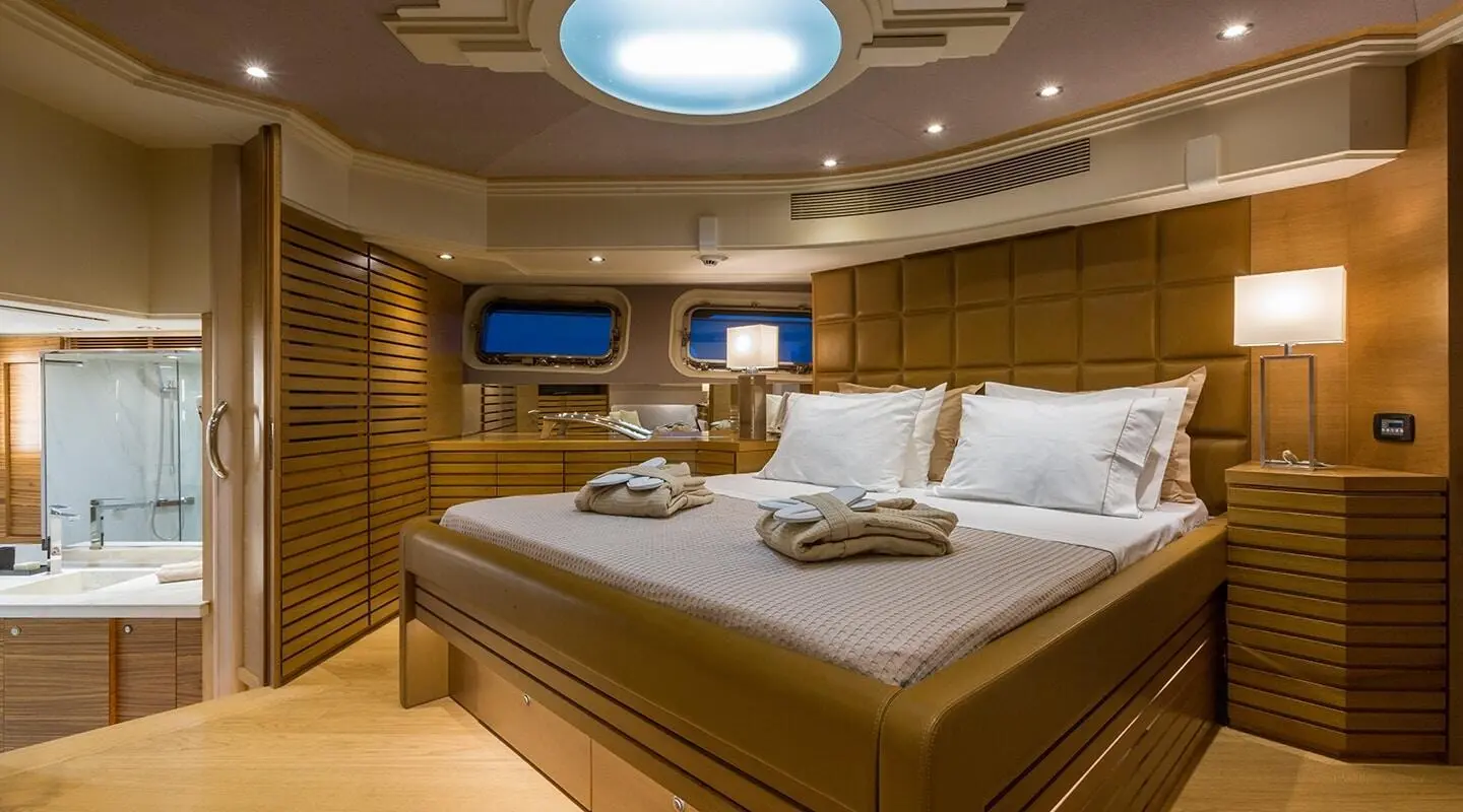 Aquarella luxury yacht bedroom with large bed, warm lighting, and ocean view screens