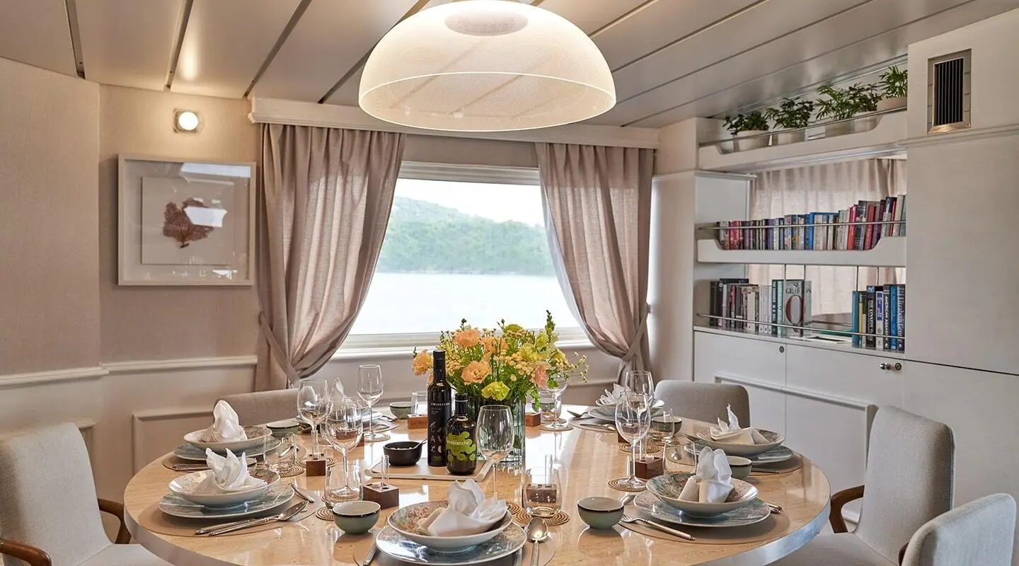 La Perla yacht dining area at sunset with table set for guests and ocean view