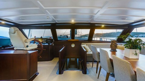Virtuoso gulet saloon with wooden furniture, helm console and side windows