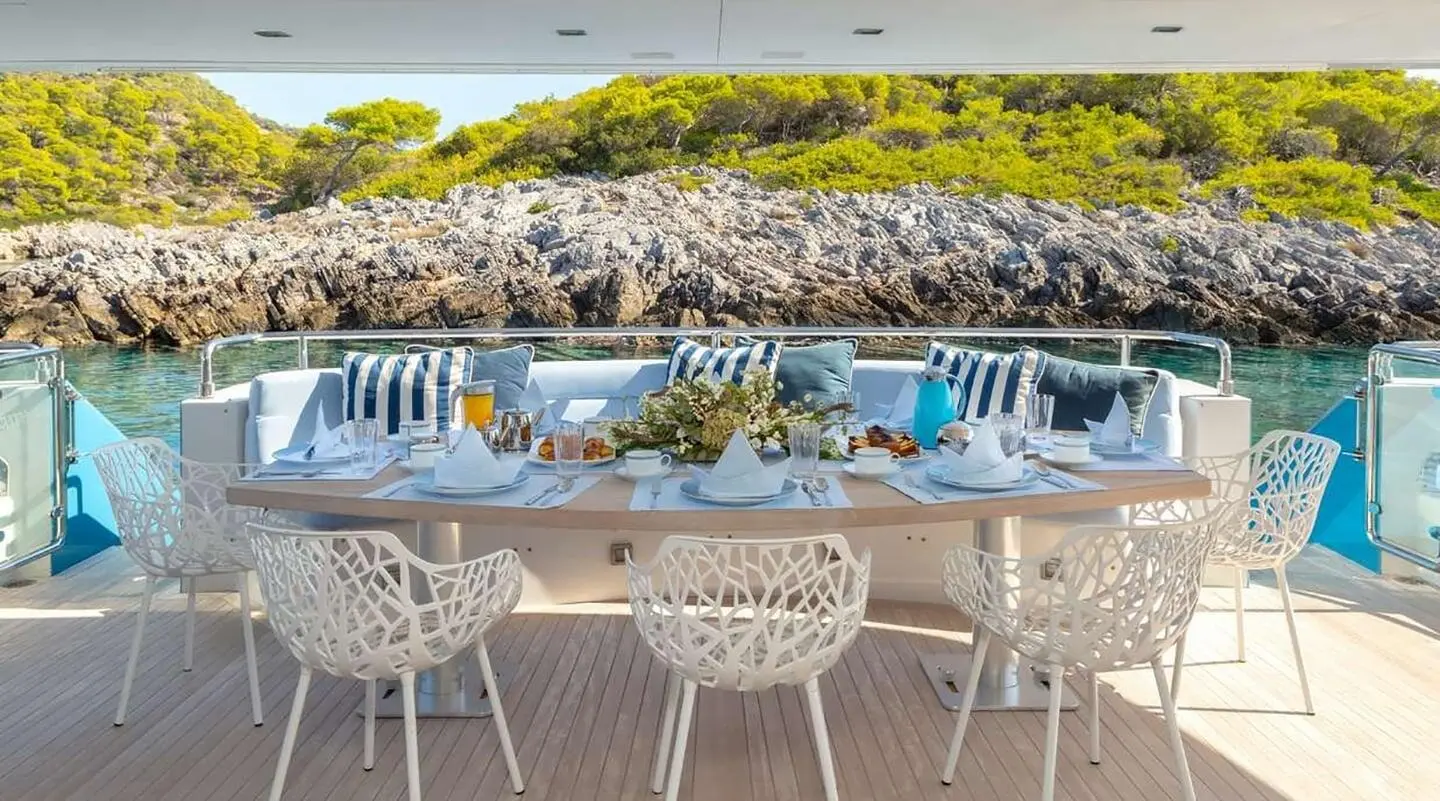 Sea Wolf yacht dining on deck with white chairs and blue cushioned seating