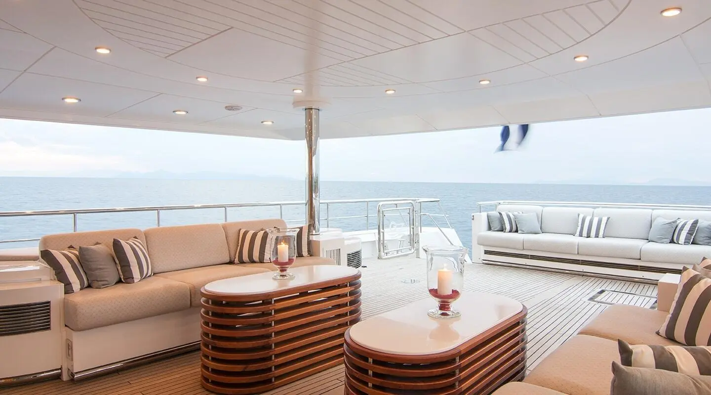 O'Natalina yacht deck seating with striped cushions under a sunlit railing at sunset