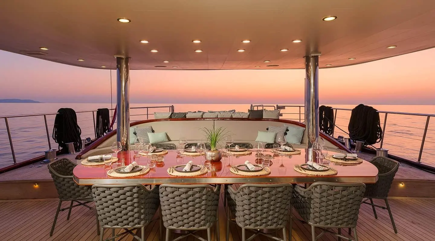 Lady Gita yacht dining area at sunset with table settings and chairs