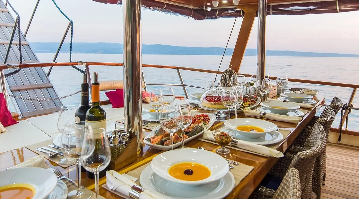 Sunset sail on Altair: elegant dining setup on deck with wine, plates, and ocean view