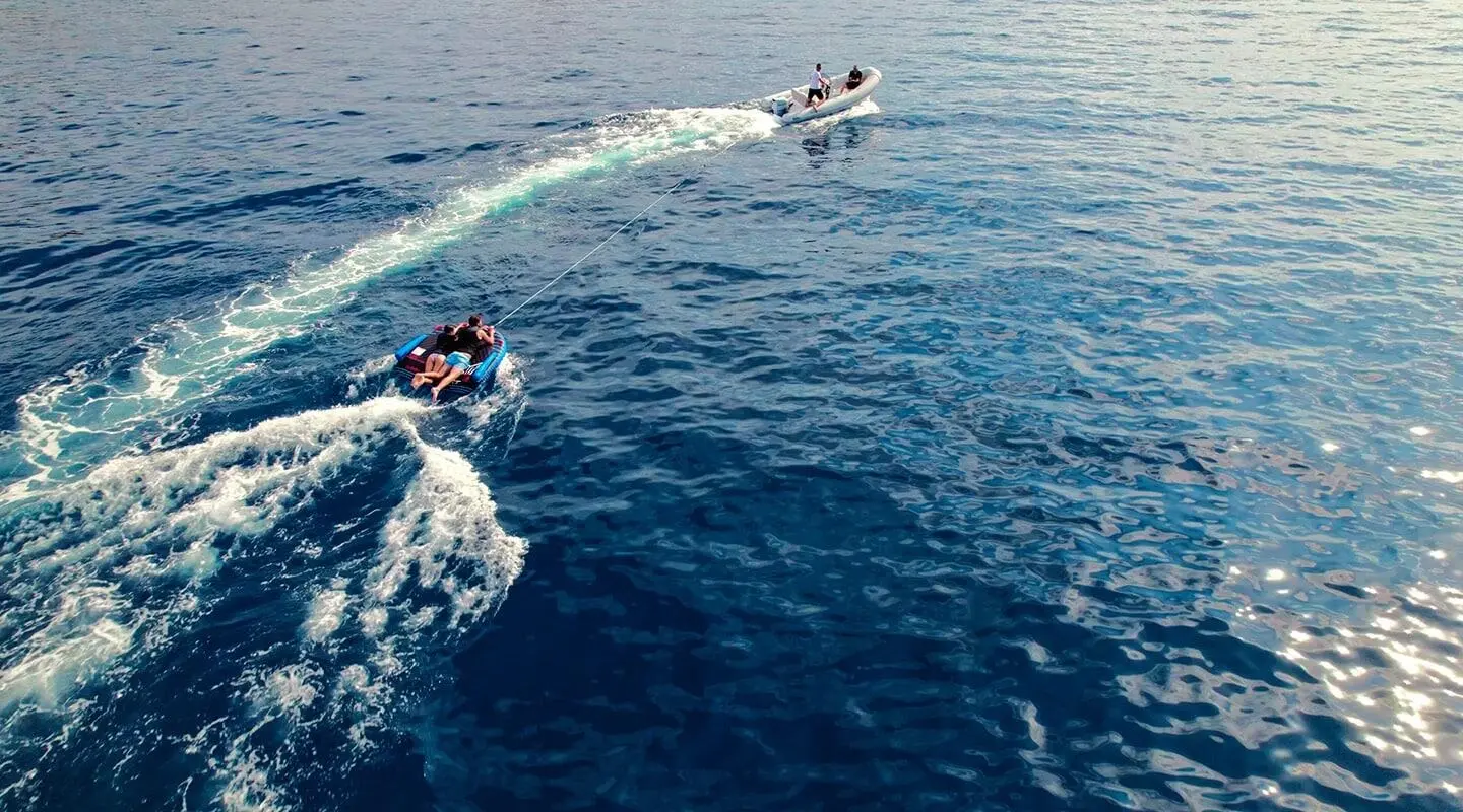 Motor yacht on the sea towing inflatable boat with passengers