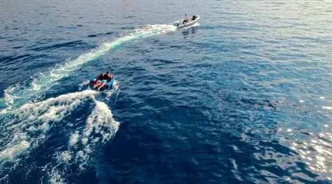 Motor yacht on the sea towing inflatable boat with passengers