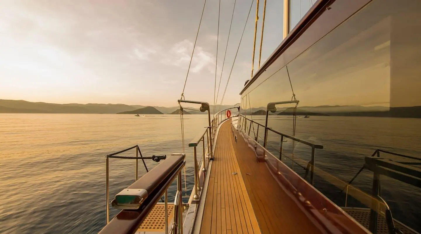 On a teak deck beside the yacht railing, sunset over calm water