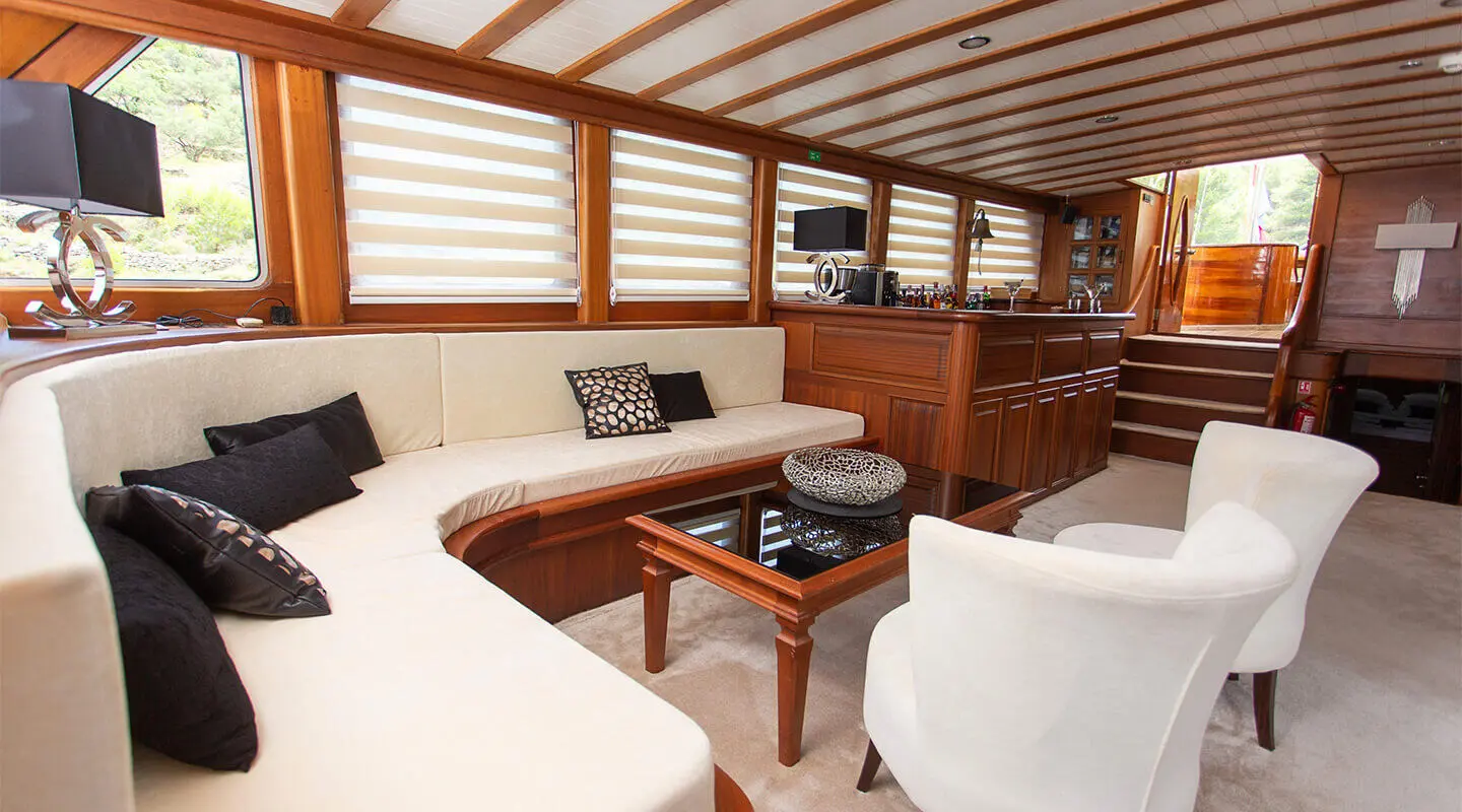 Luxurious yacht Dolce Vita salon with light wood and white cushions, teak table