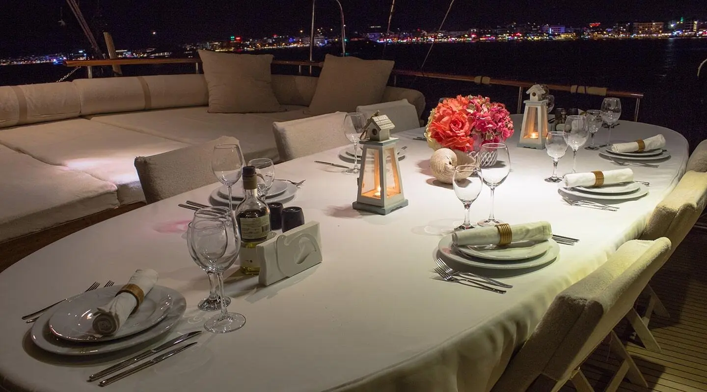 Derin Deniz yacht seen at sunset with dining table set for guests on deck