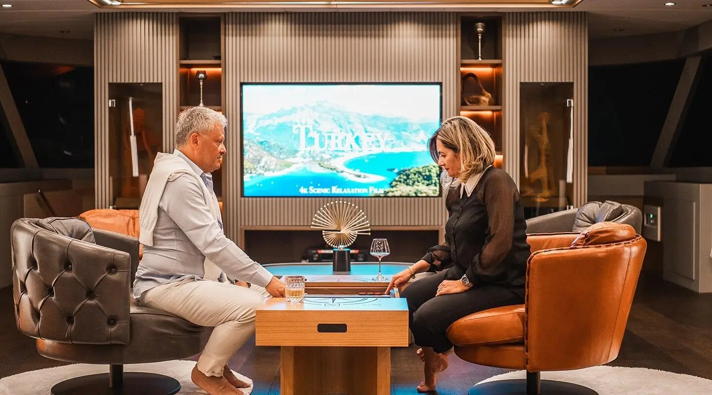 Inside salon of North Wind yacht; two people seated facing large screen map