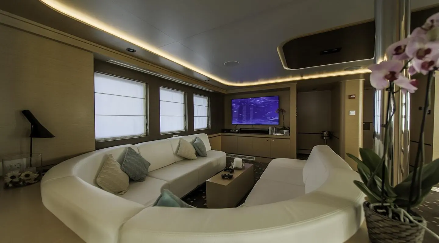 Interior view of Omnia yacht lounge with white seating and TV screen