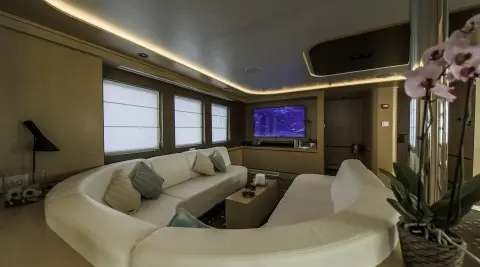 Interior view of Omnia yacht lounge with white seating and TV screen