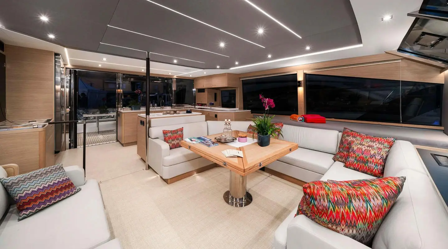 Luxurious yacht salon with white seating, wooden coffee table, and warm lighting