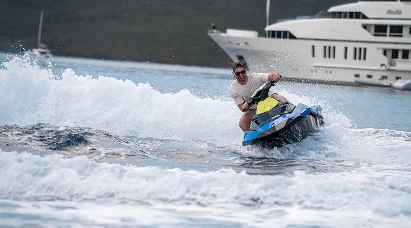 Cristal yacht on the water with a person riding a jet ski near waves