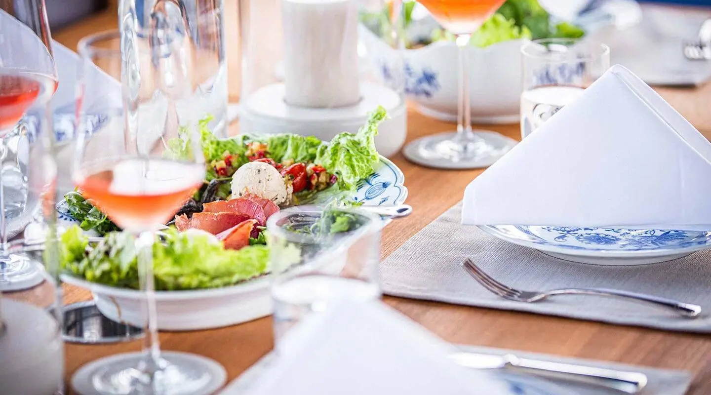 Insieme yacht dining scene with plated meals on a sunlit table aboard