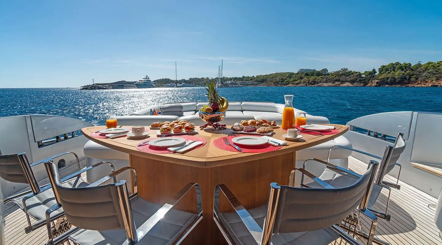 Table on a yacht deck with dishes, glasses, and a blue sea view