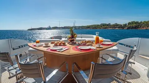 Table on a yacht deck with dishes, glasses, and a blue sea view