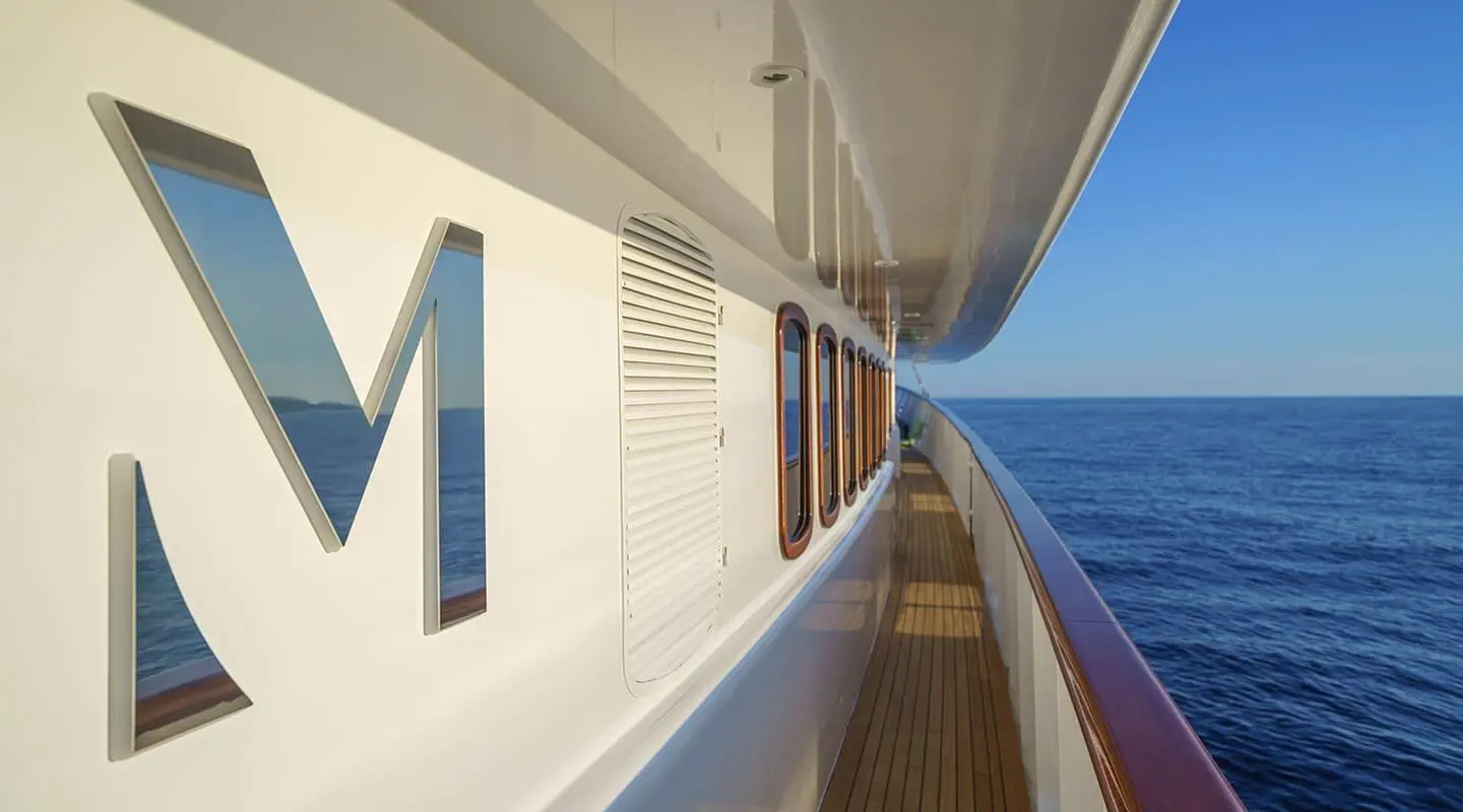 Side deck of Maia motor yacht with rails, ocean view, and blue sky