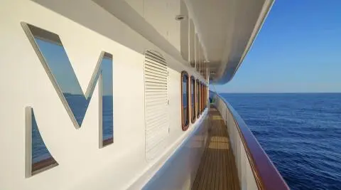 Side deck of Maia motor yacht with rails, ocean view, and blue sky