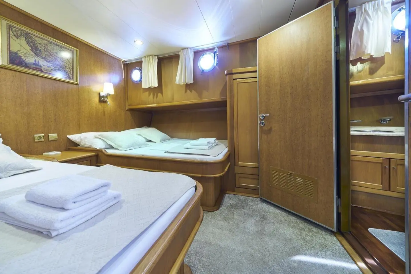Interior of a gulet yacht with twin cabins, wooden walls, and porthole windows
