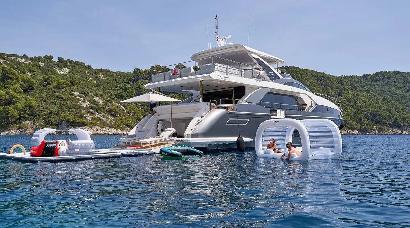 Luxurious Aluminia Too yacht anchored with smaller tenders beside on calm blue water