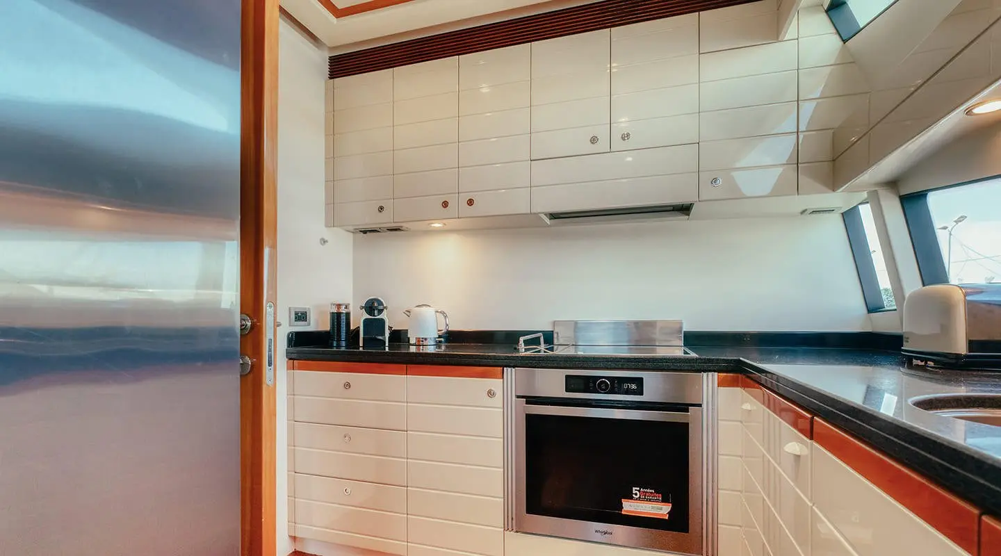 Compact yacht kitchen with white cabinets, built-in oven, and dark countertop