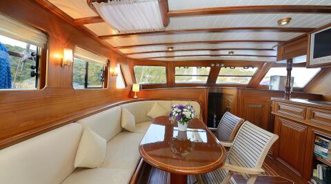 Samarkand yacht interior: polished wood panels, cream seating, and a glossy dining table with a flower centerpiece