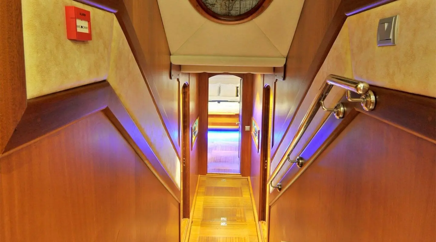 Wood-paneled indoor corridor with stairs and a doorway at the end.