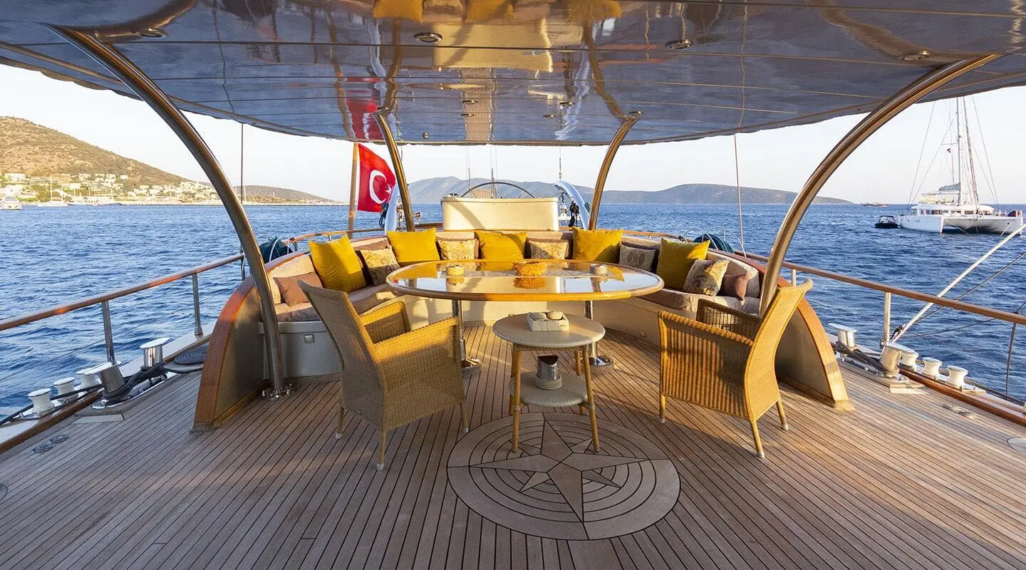 View of boat dining area on aft deck with yellow cushions and shade sails