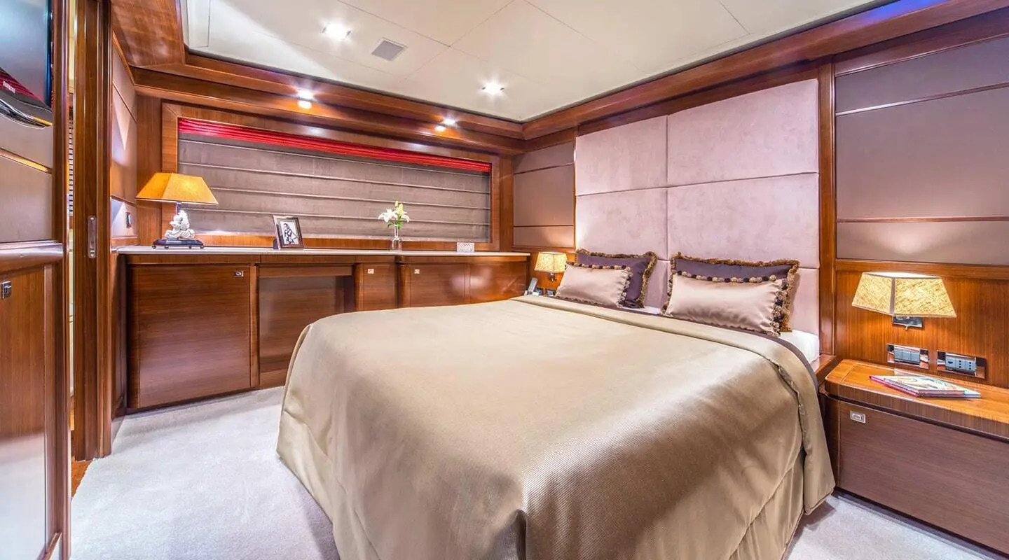 Seventh Sense yacht bedroom with large bed, warm lighting, and wood paneling