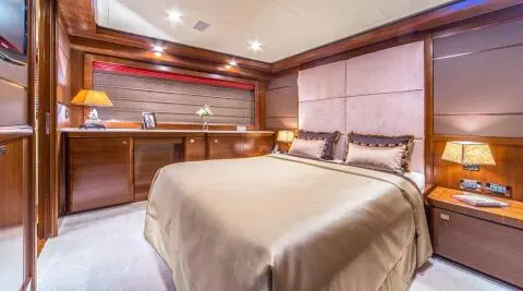 Seventh Sense yacht bedroom with large bed, warm lighting, and wood paneling