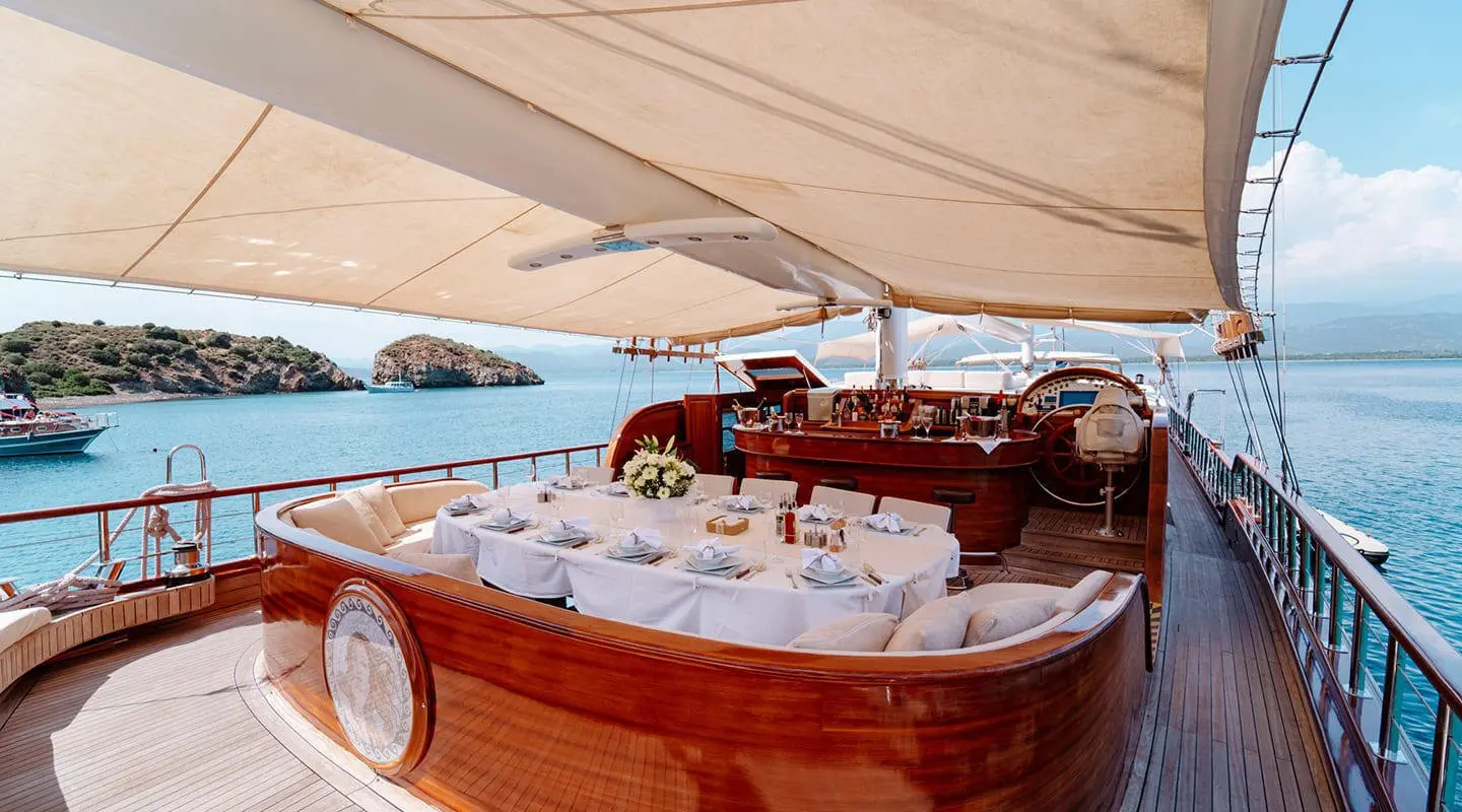 Lycian Queen yoga? No. A luxury wooden gulet with white seating under awning at sunset