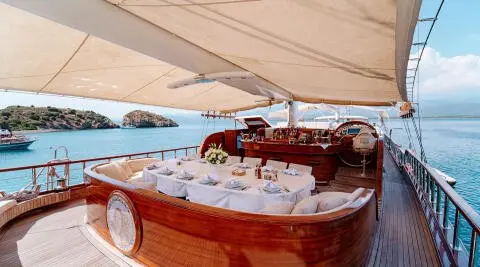 Lycian Queen yoga? No. A luxury wooden gulet with white seating under awning at sunset