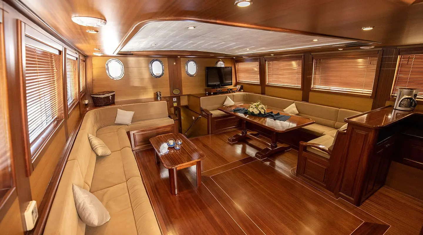 Kayhan 4 yacht interior with polished wooden deck and seating area on a sunlit voyage