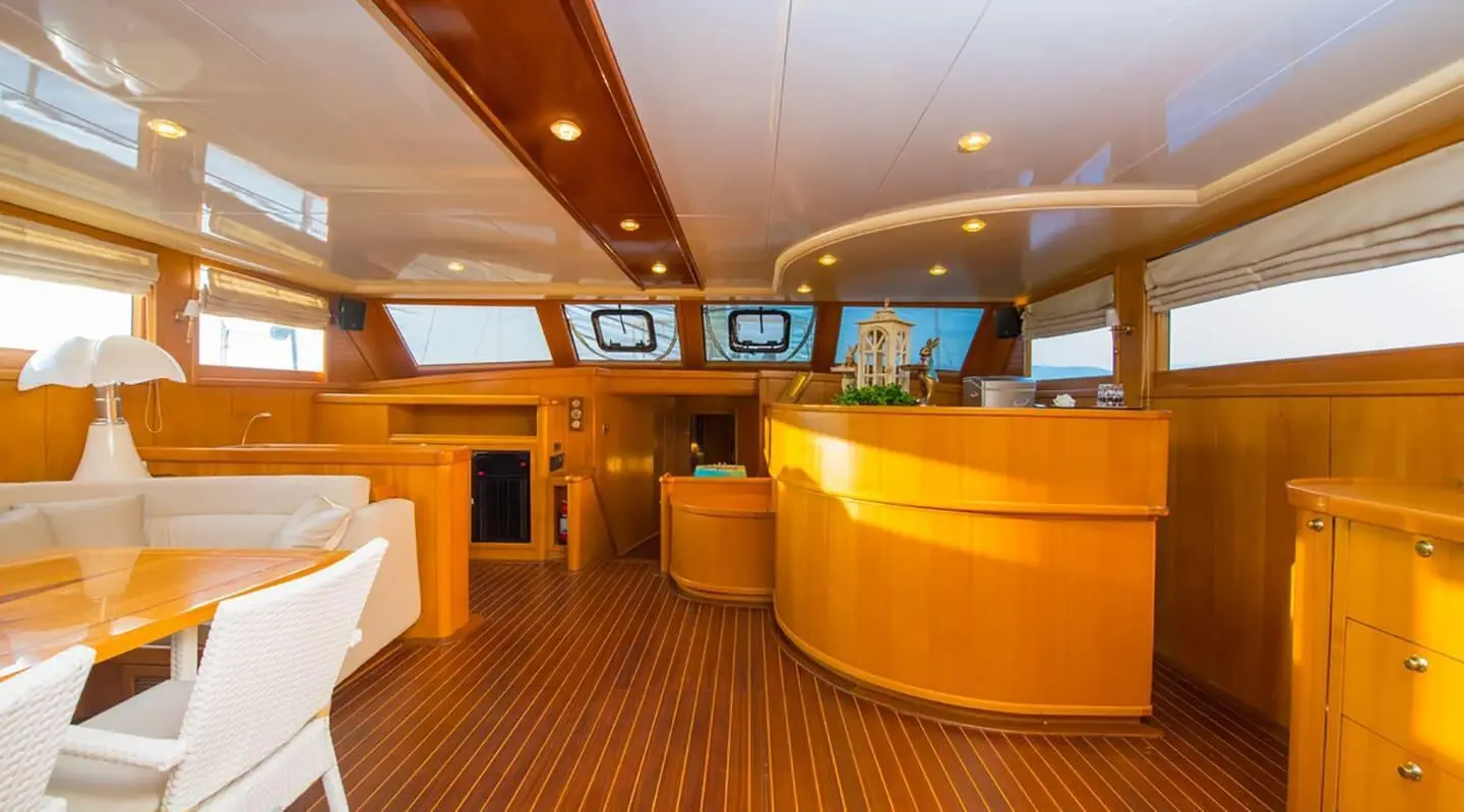 Yacht Mein Schatz interior: polished wooden deck, curved seating, helm, soft lighting