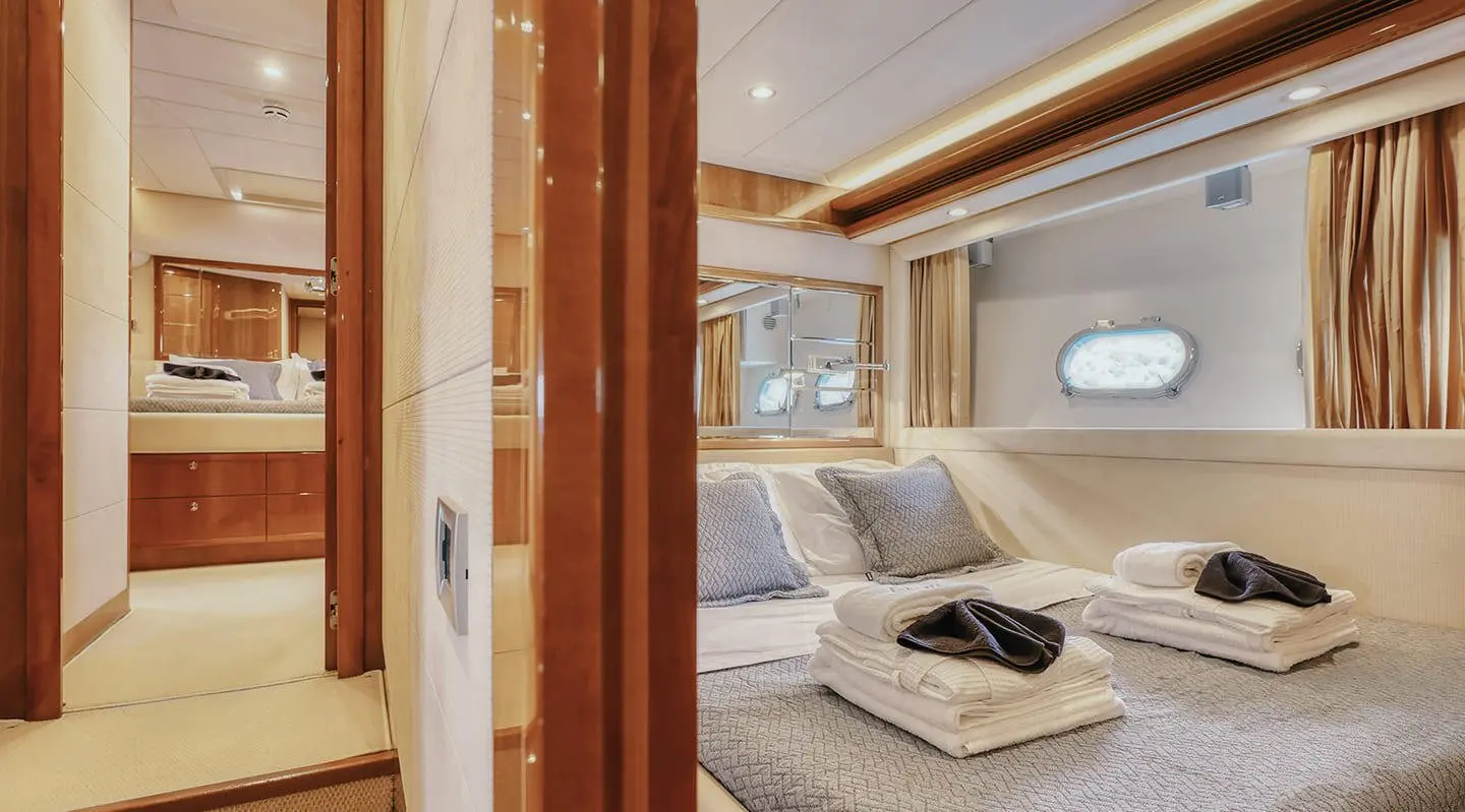 Lidia yacht interior bedroom with cream bedding, wooden accents, and porthole window