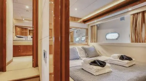 Lidia yacht interior bedroom with cream bedding, wooden accents, and porthole window