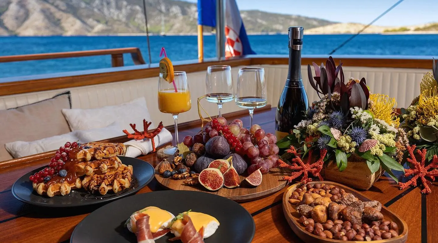 Aborda yacht with a table of seafood and drinks on deck at sunset