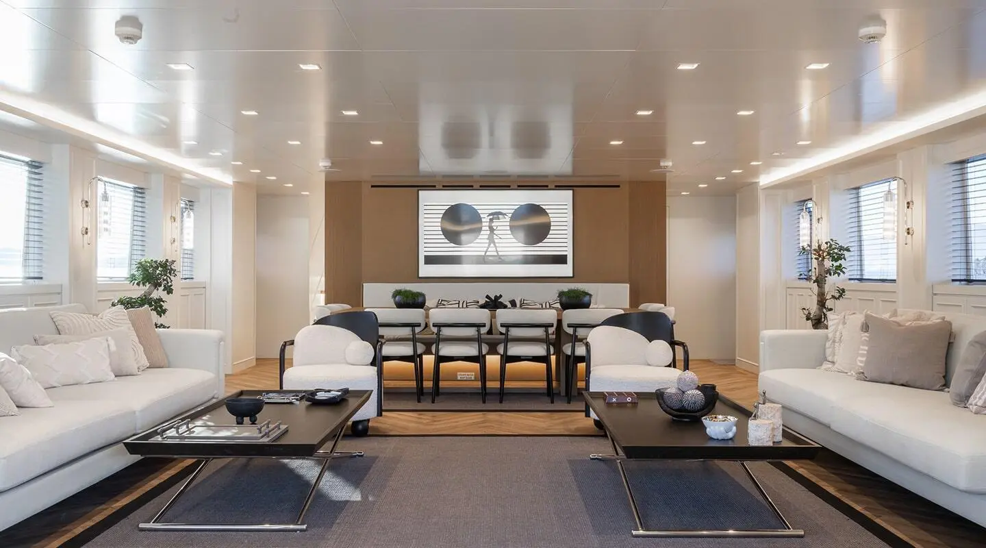 Interior yacht saloon with seating area, coffee table, and large windows