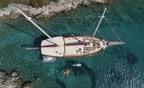 A luxury Morning Star sailing yacht anchored near rocky coastline with clear turquoise water