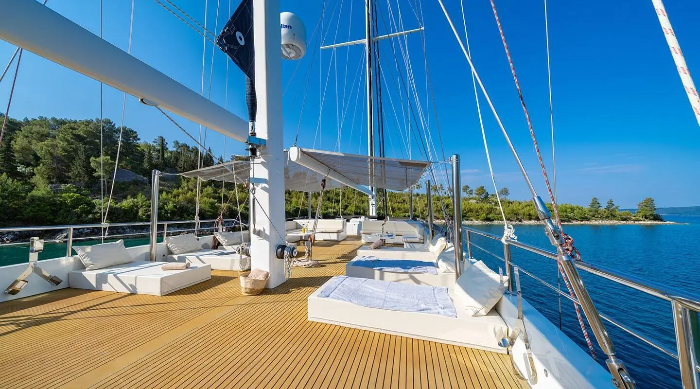 Navilux motoryacht deck with sun loungers and rigging, sunlit marina scene