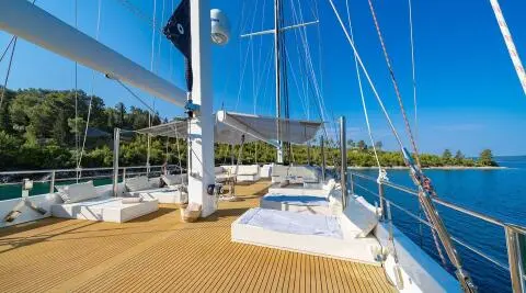 Navilux motoryacht deck with sun loungers and rigging, sunlit marina scene
