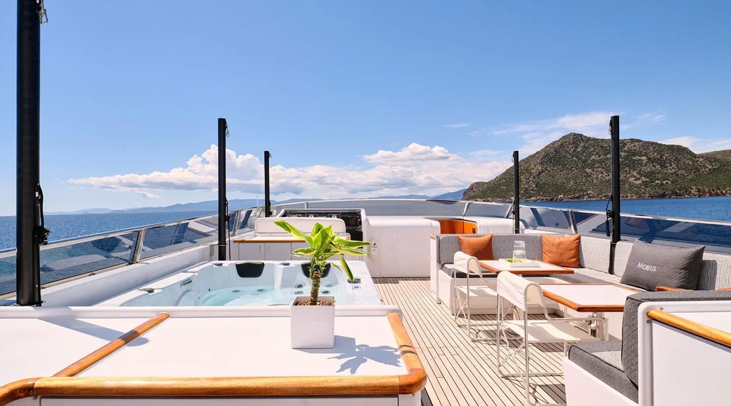 Mobius yacht deck with sun loungers, white seating, and a jacuzzi on a sunny day