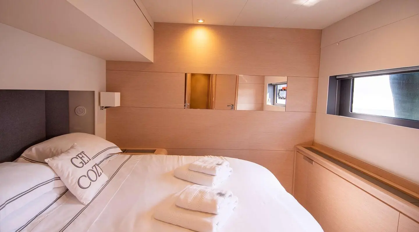 Interior of Serenissima yacht with two neatly made beds and warm lighting